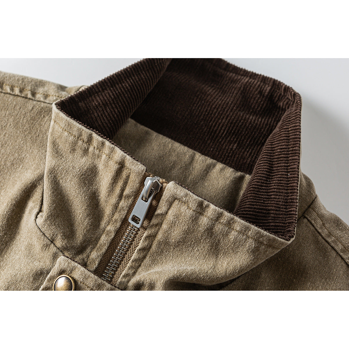 Close-up of a tan jacket's dark brown ribbed stand collar and front zipper.