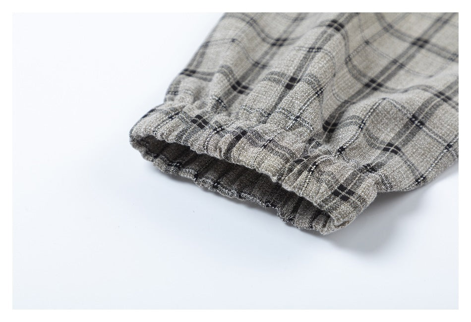 Close-up of a gathered edge on gray-beige plaid fabric with dark intersecting lines.