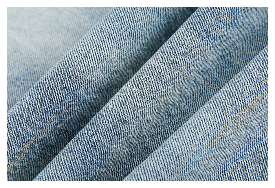 Close-up of blue denim fabric with a diagonal twill weave and folded ridges.