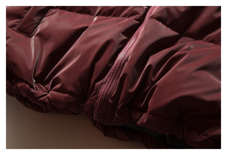 Close-up of a burgundy puffer jacket's front zipper and gathered hem.