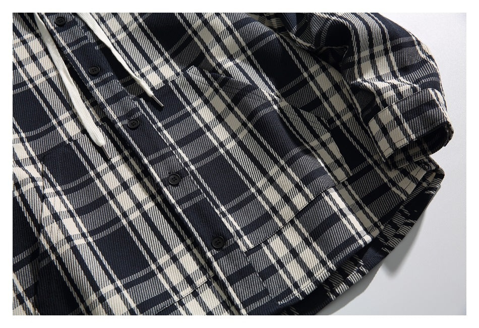 Close-up of a black, cream, and gray plaid button-front shirt showing its placket, sleeve, and hem.