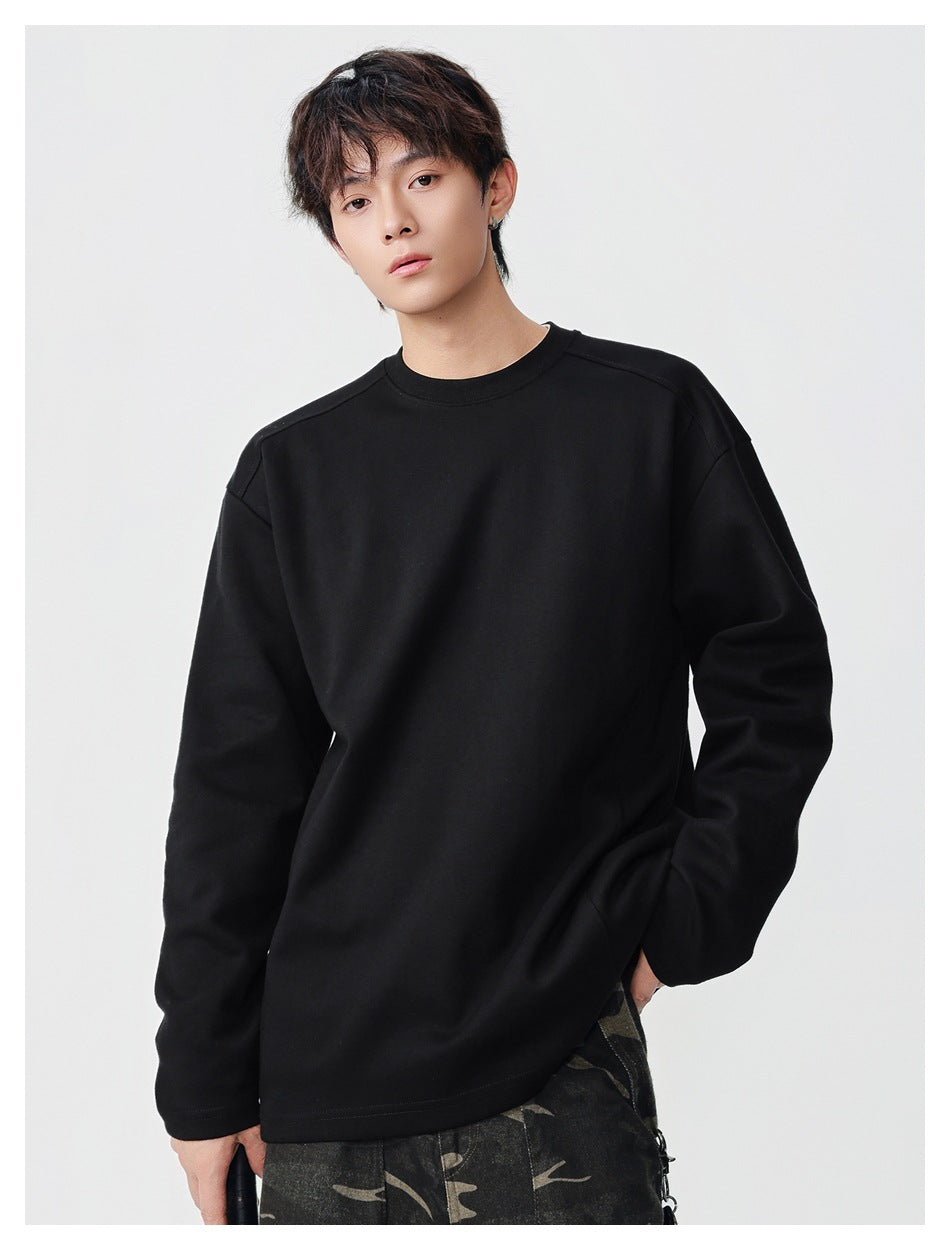 Model wearing an oversized black crewneck top with long sleeves and a plain front.