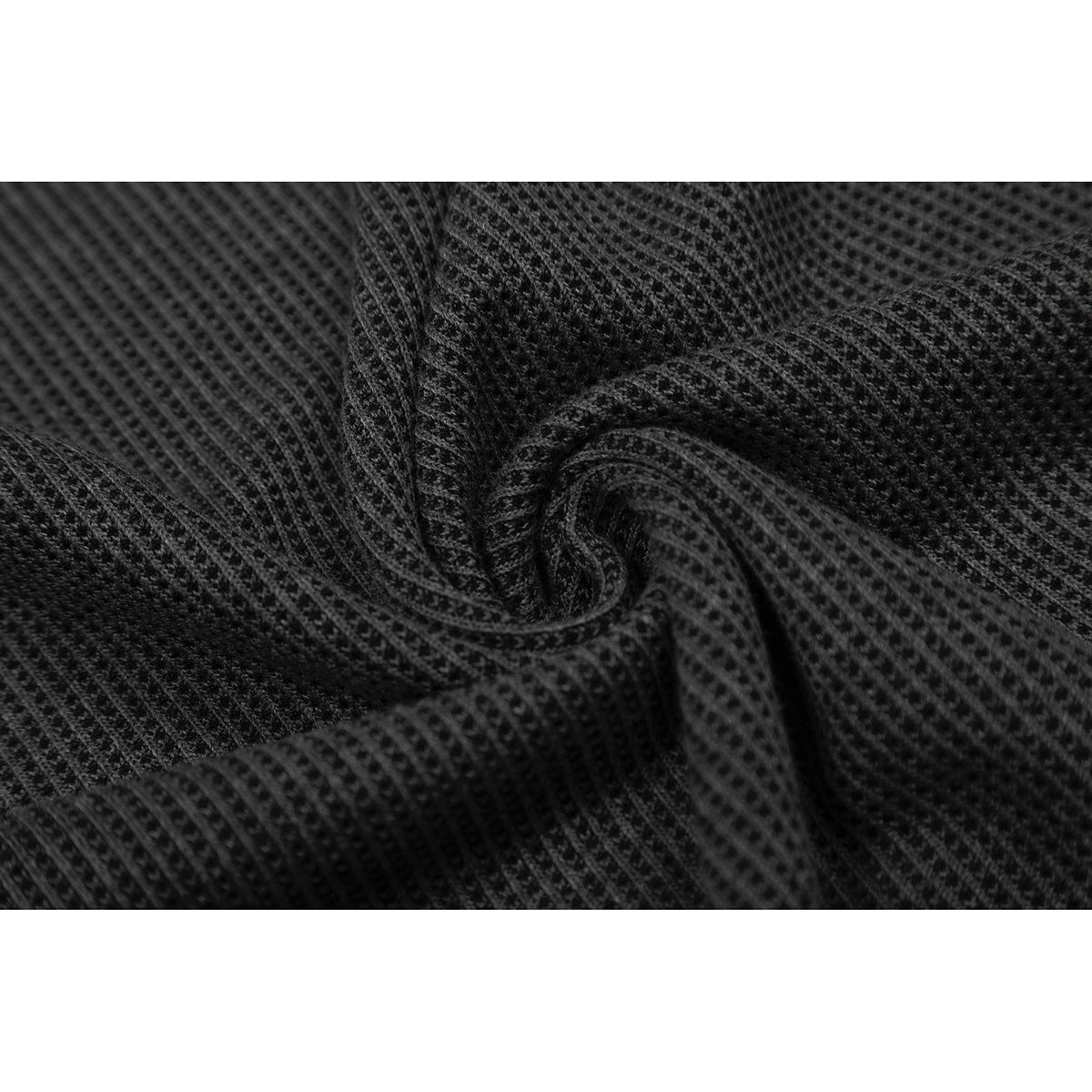Macro view of charcoal waffle-knit fabric gathered to show its textured surface.