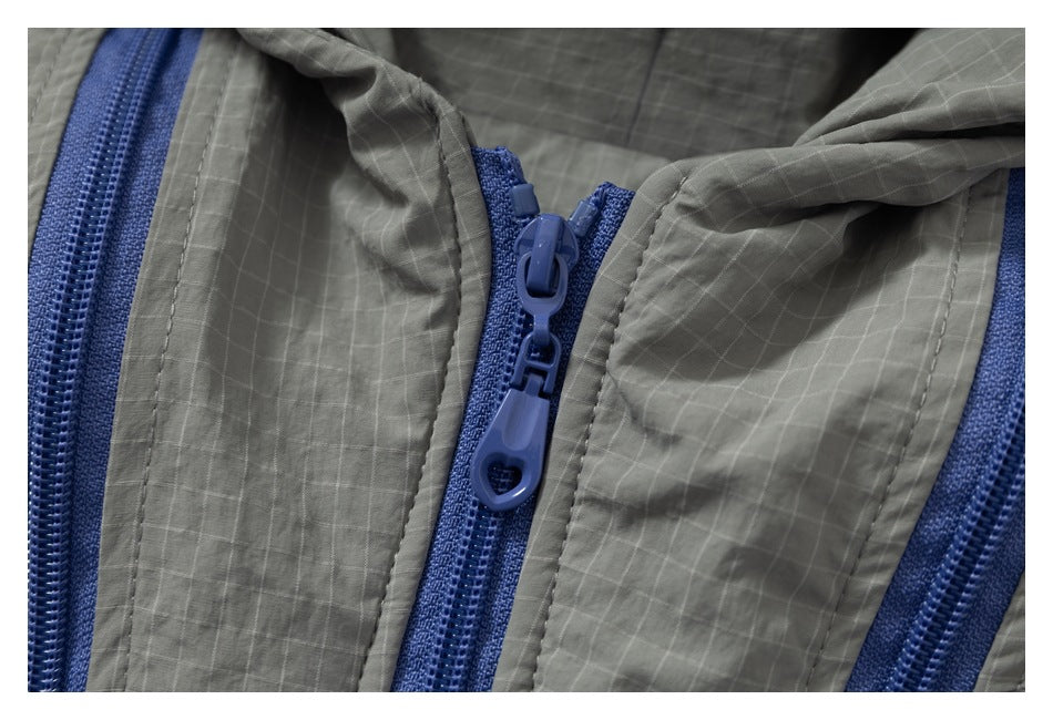 Close-up of blue zipper pulls and parallel zippers on gray grid-patterned fabric.