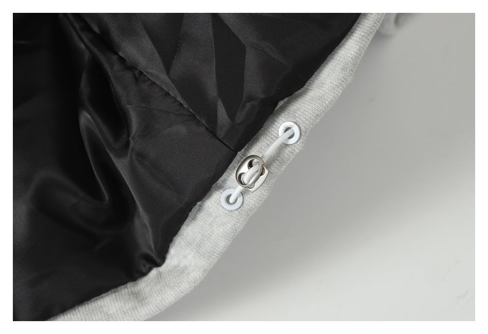 Close-up of a light gray garment edge with black lining and a small cord-and-loop fastener.