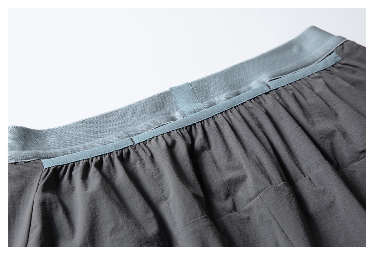 Close-up of the pale blue waistband and gathered charcoal fabric on the shorts.
