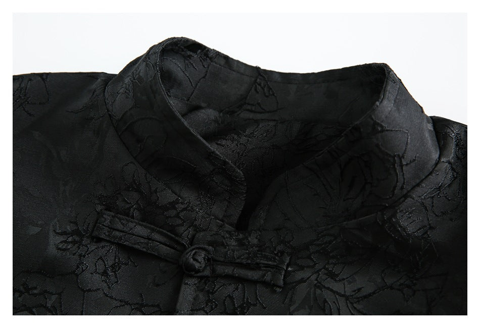 Close-up of a black jacket's stand collar, floral pattern, and knotted frog closure.