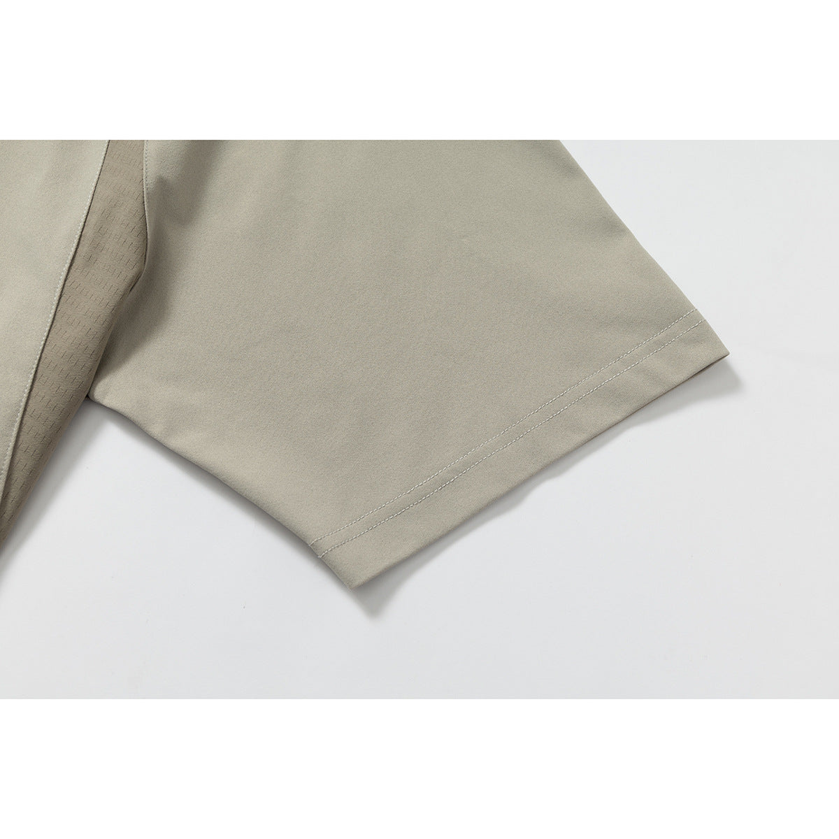 Close-up of a taupe short sleeve hem with double stitching and a patterned underarm panel.