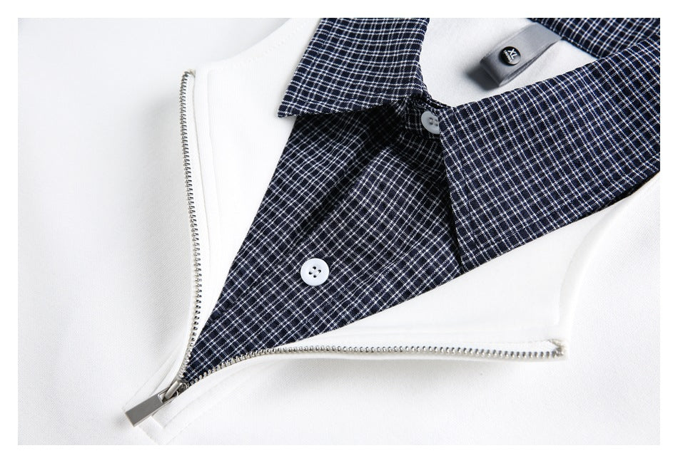 Close-up of a white zip-front garment with a navy checked collar, buttons, and silver zipper.