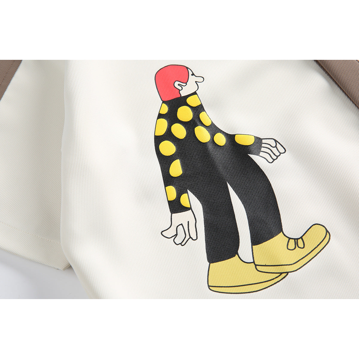 Close-up of a cartoon figure with a red head, yellow polka dots and yellow shoes printed on white fabric.