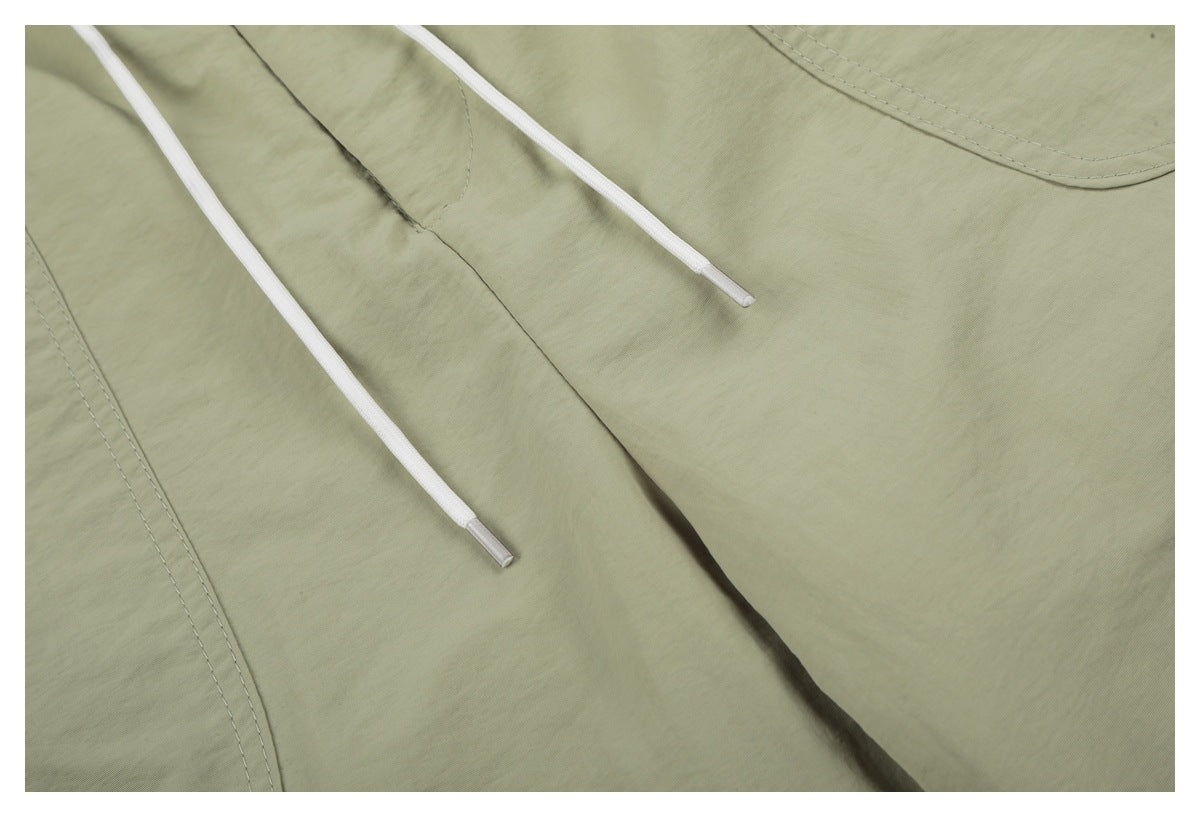Close-up of sage-green shorts showing white drawstrings, front seam and pocket stitching.