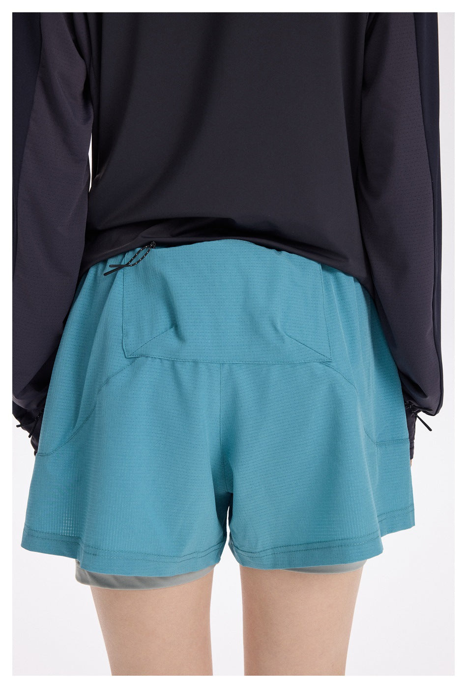 Rear view of a model wearing turquoise running shorts with a large back pocket and gray inner shorts.
