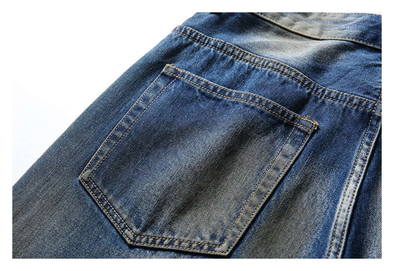 Close-up of a back patch pocket on blue faded jeans with contrast stitching.