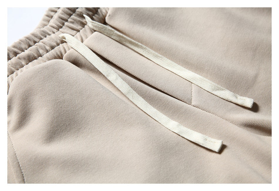 Close-up of cream drawstrings and the elastic waistband on beige shorts.