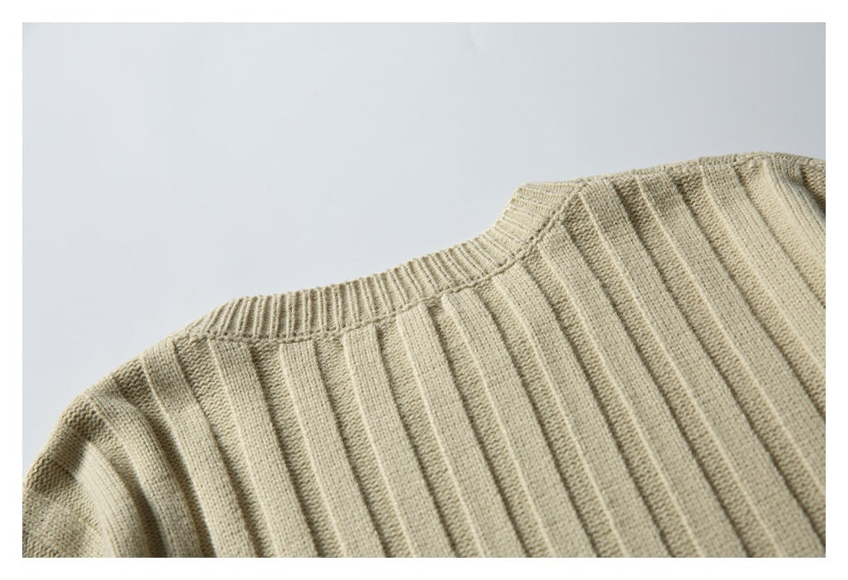 Close-up of a beige ribbed knit sweater showing the crew neckline and shoulder.