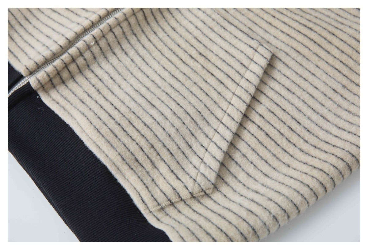 Close-up of a seam and pocket on cream striped fabric, with a black ribbed edge.