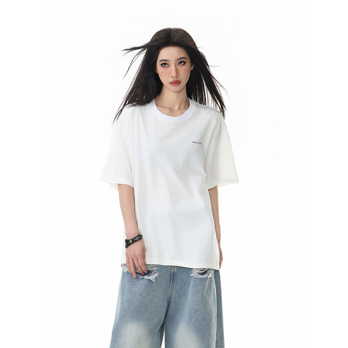 Model wearing an oversized white short-sleeve crew-neck T-shirt with small dark chest text, shown from the front.