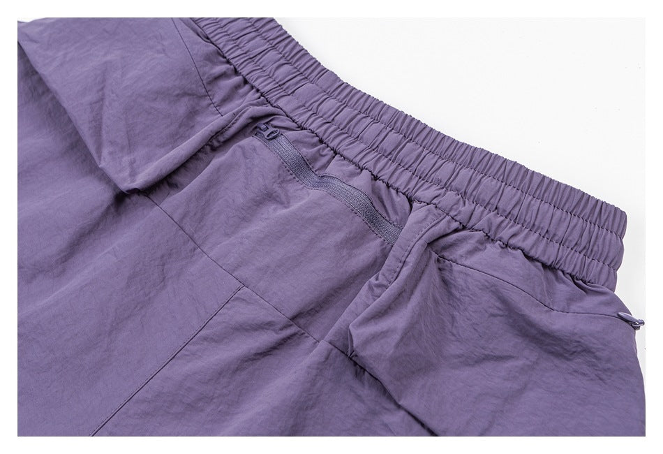 Close-up of purple pants with a gathered elastic waistband and a small zippered pocket below it.