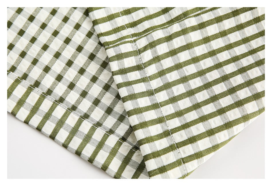 Close-up of the checked garment's stitched hem and seam in olive green and cream.