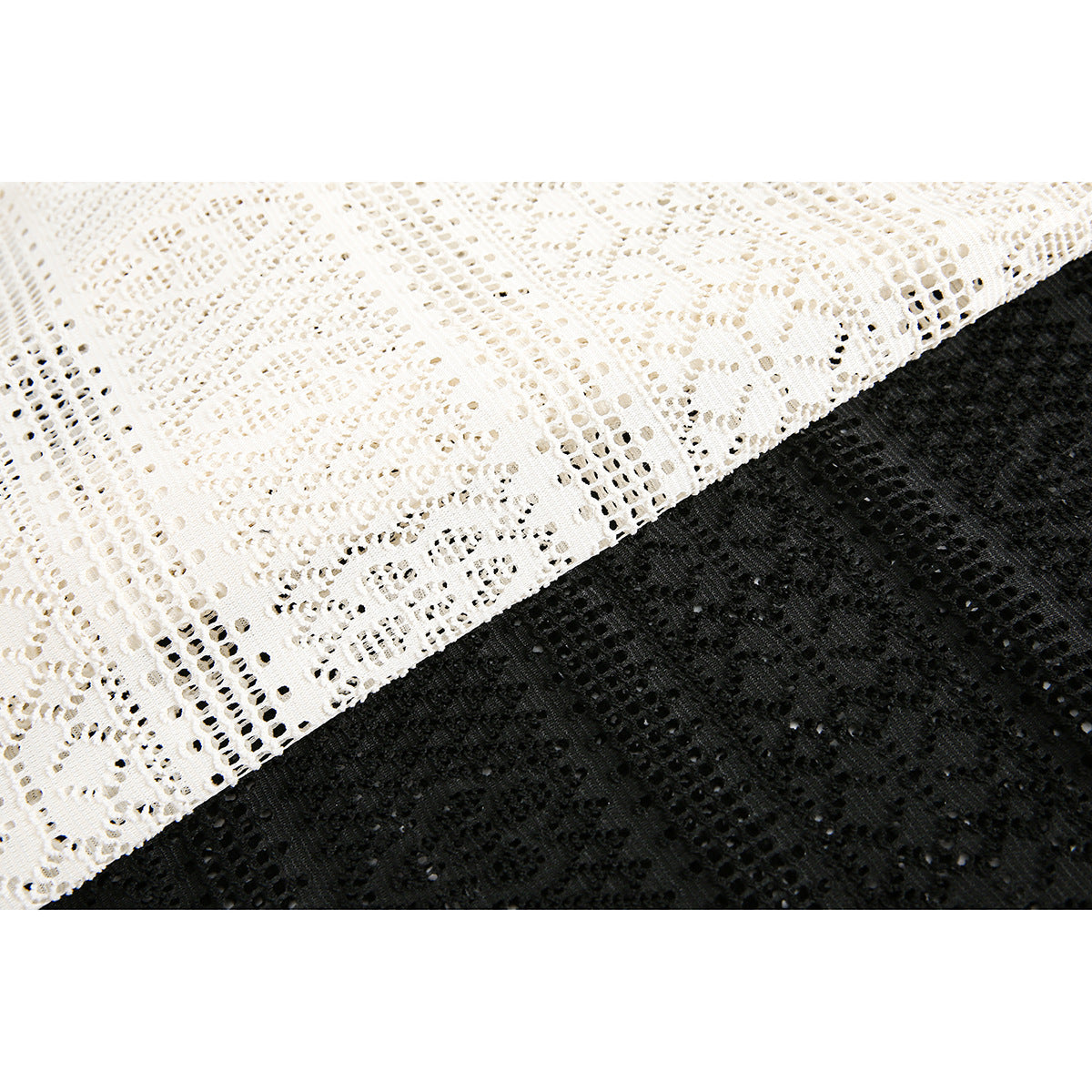Close-up of cream and black openwork fabric with repeating geometric and floral patterns.