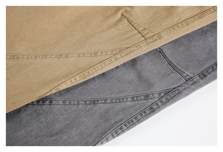 Close-up of tan and charcoal gray pants overlapping, showing fabric texture and curved stitching.