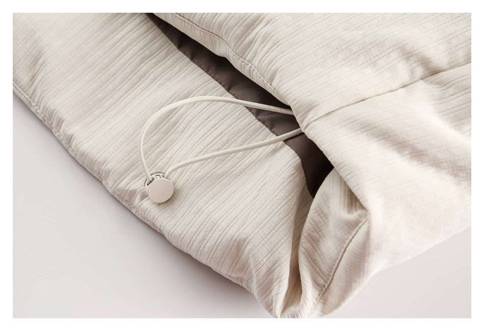 Close-up of an ivory jacket's adjustable cord and toggle near the hem.