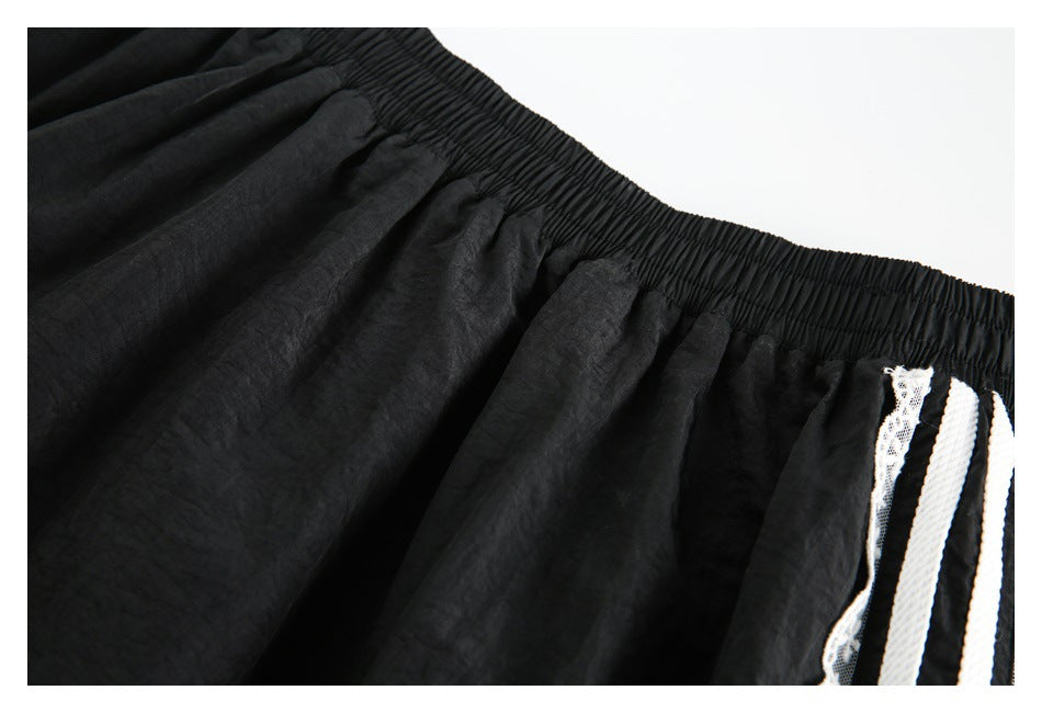 Close-up of a gathered elastic waistband on black bottoms, with white striped lace trim at the side.