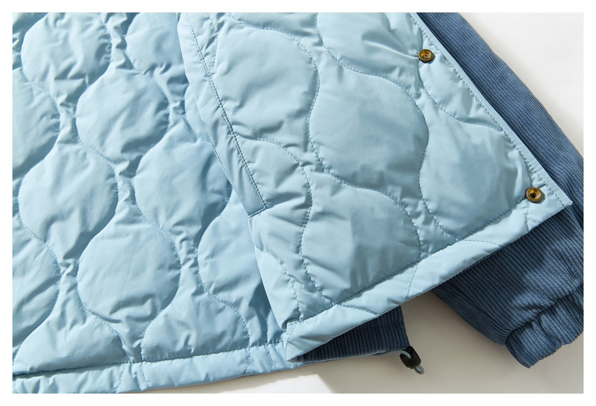 Close-up showing the jacket's light blue rounded quilting, blue ribbed exterior, and metal snaps.