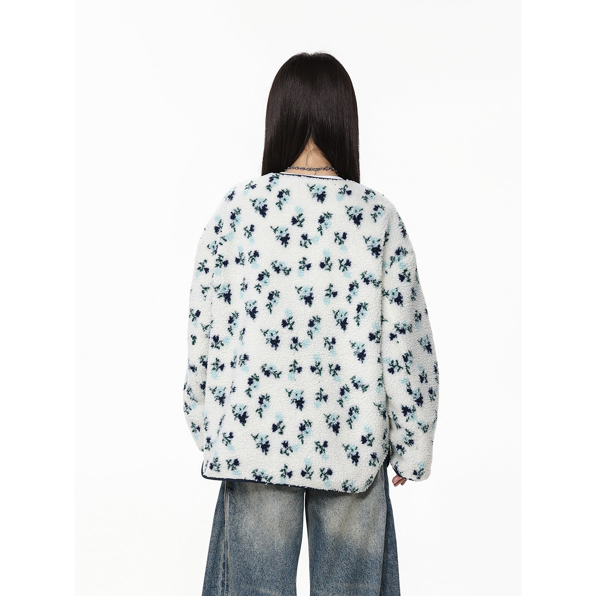 Rear view of a model wearing a white floral fleece jacket with navy edging and loose blue jeans.