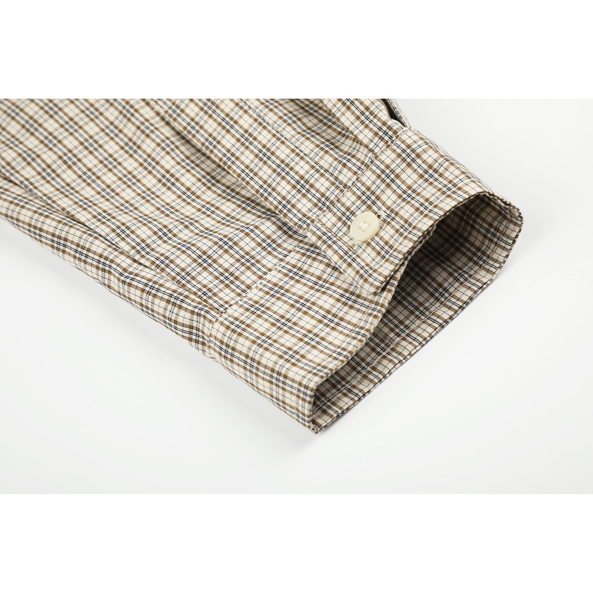 Close-up of a plaid shirt sleeve cuff with a cream button.