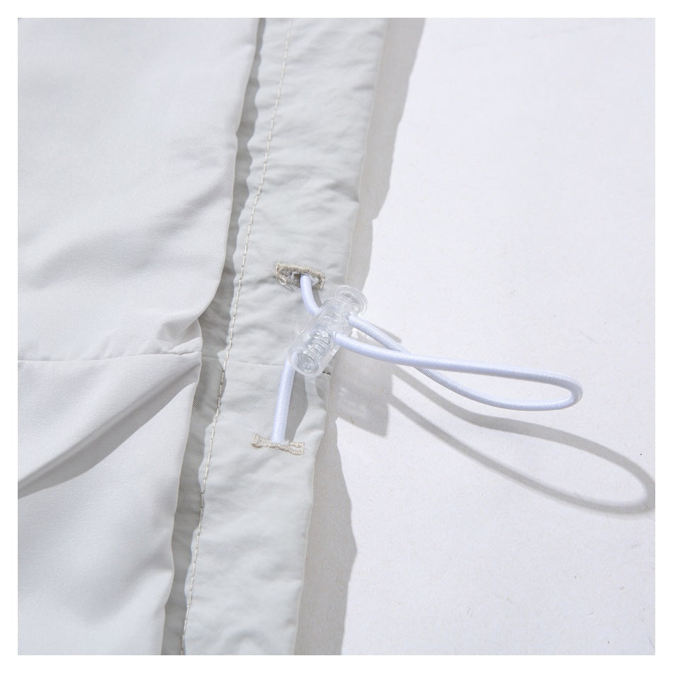 Close-up of a white garment seam with a cord loop and clear plastic adjustment toggle.
