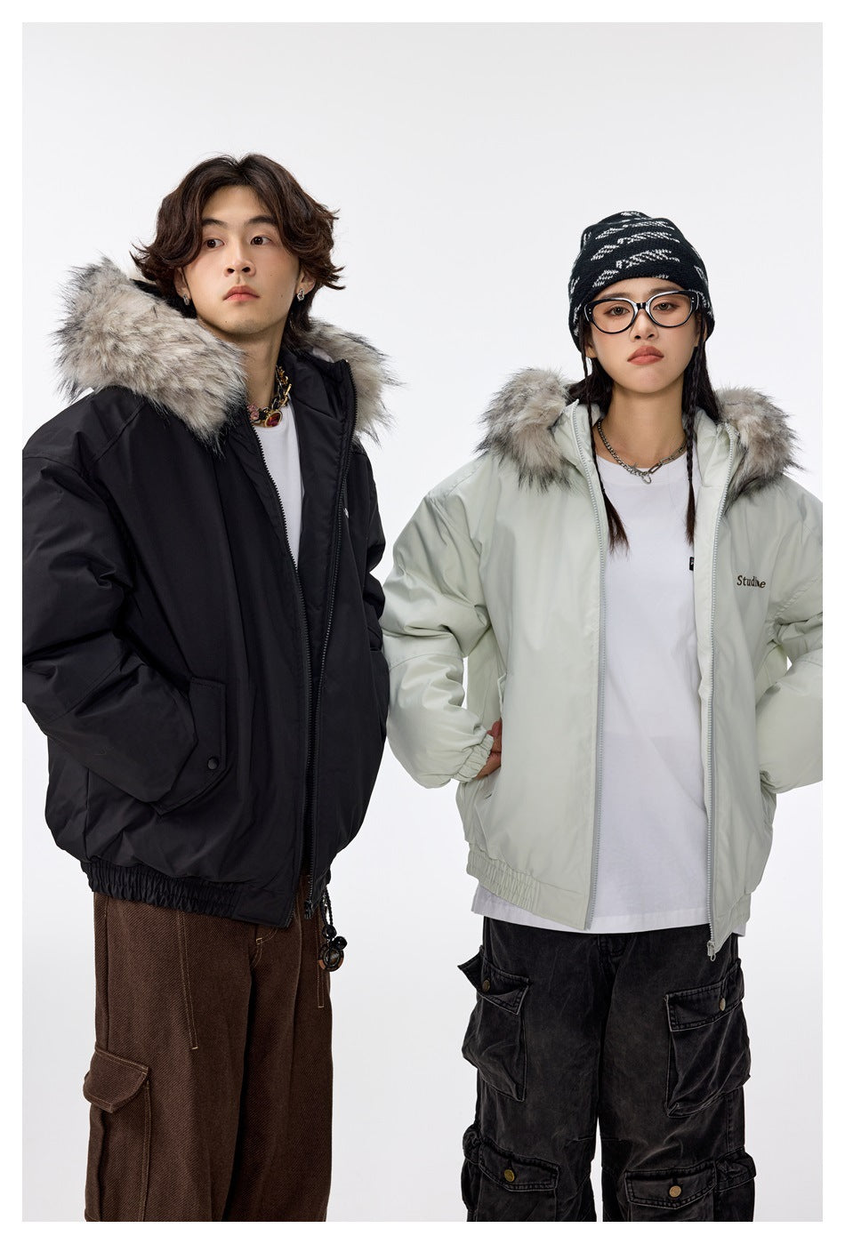 Two models wearing black and light green hooded jackets with fur-style trim over white tees and cargo pants