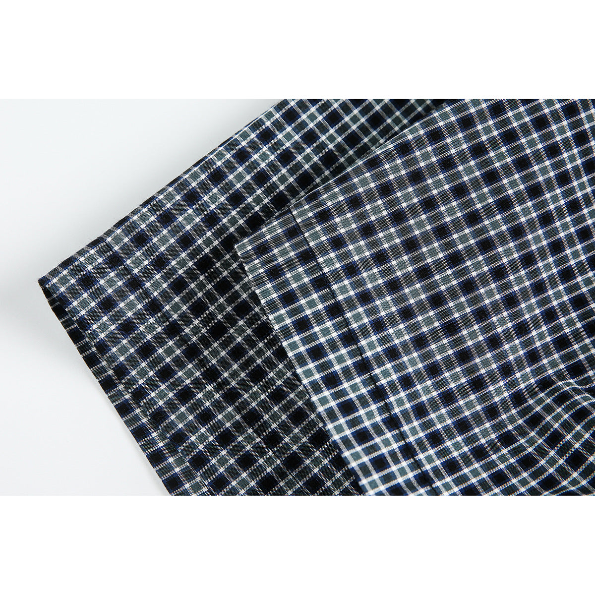 Close-up of the checked shirt's short sleeve and seam against a white background.