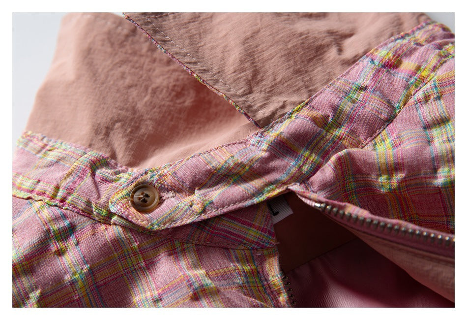 Close-up of the jacket’s plaid collar edge, brown button, zipper, and smooth inner lining.