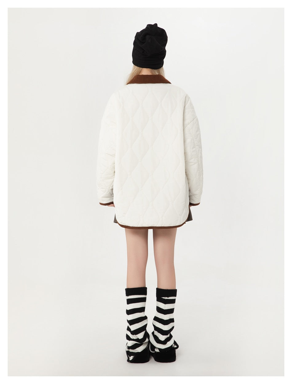 Back view of a model wearing an ivory quilted jacket with a brown collar and hem trim.
