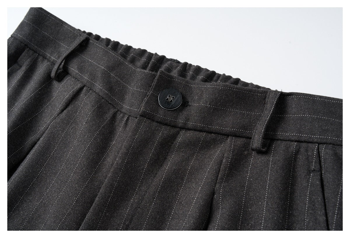 Close-up of the charcoal pinstripe trousers’ buttoned waistband, belt loops, stitching and front pleats.