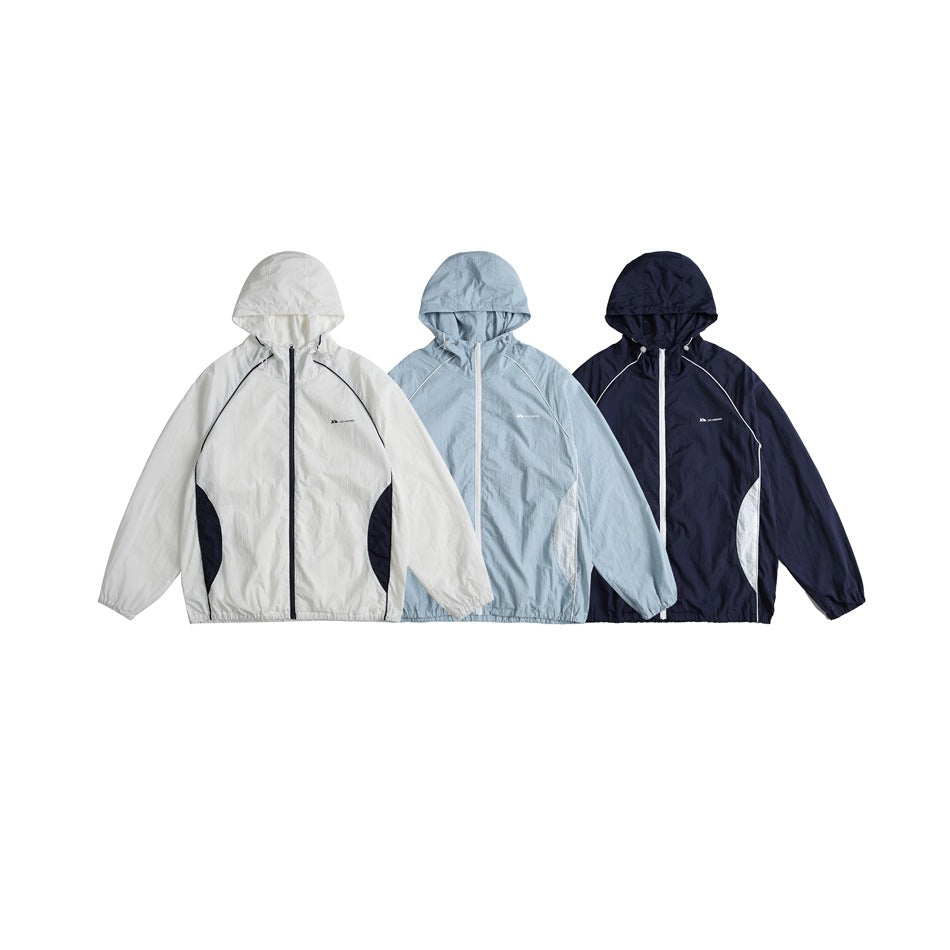Three hooded jackets shown from the front in white, pale blue and dark navy, with contrast panels and piping.