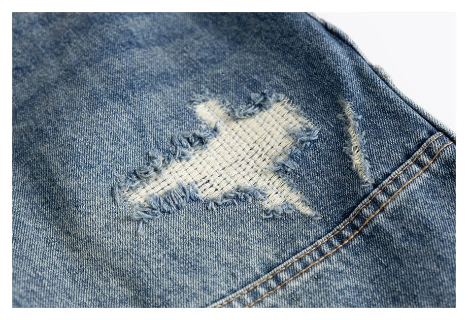 Close-up of blue jeans with a frayed, light-colored repair patch and distressed edges.