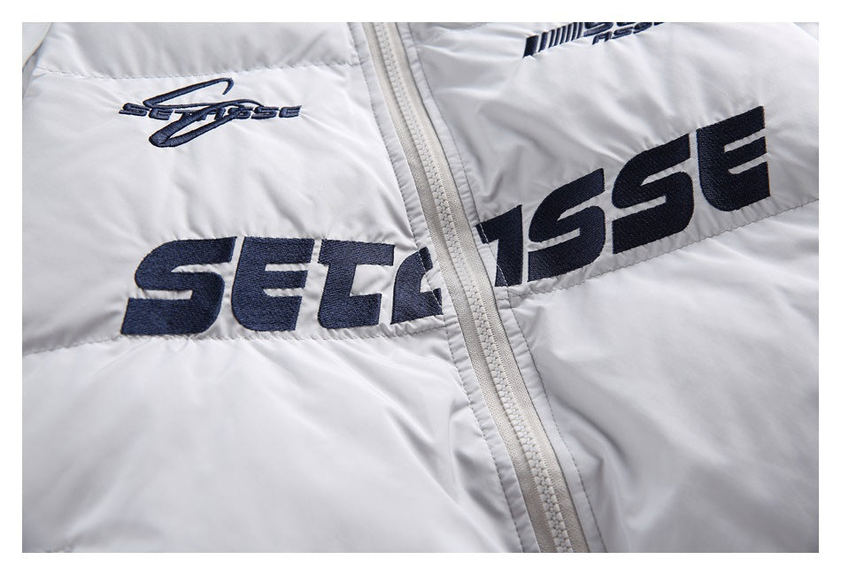 Close-up of dark embroidered lettering on the light gray jacket beside its front zipper.