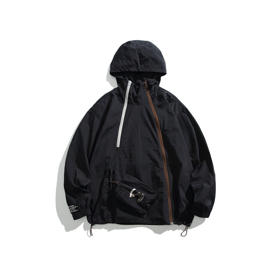 Black hooded jacket with diagonal brown and gray zippers, drawcord hem and small drawstring pouch, flat lay