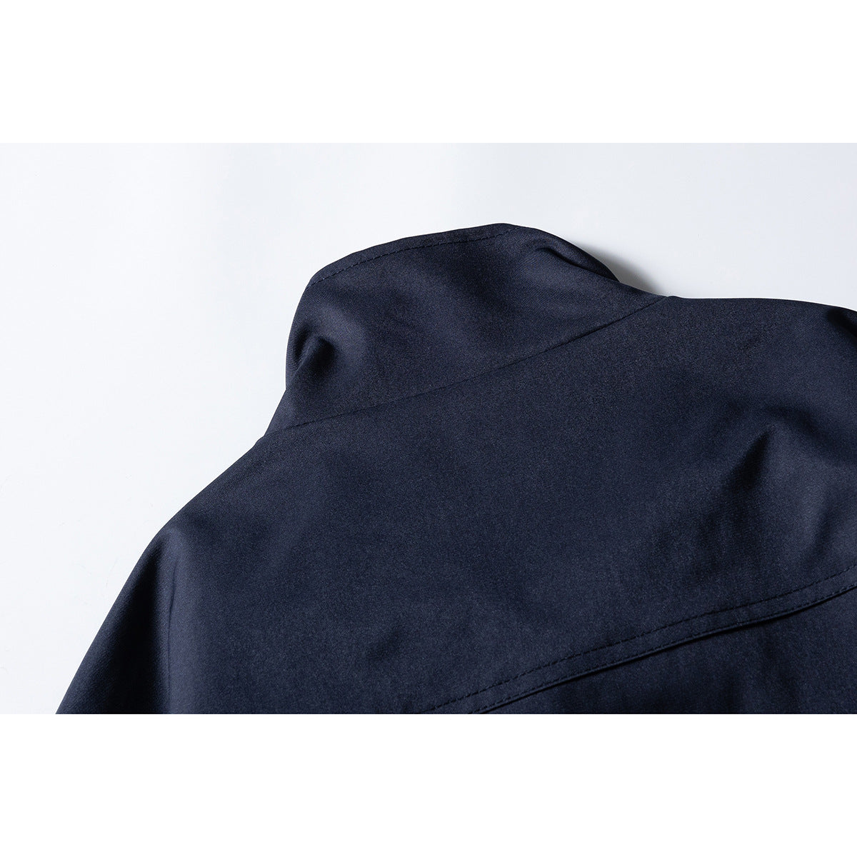 Close-up of the back yoke and raised collar of a navy jacket.