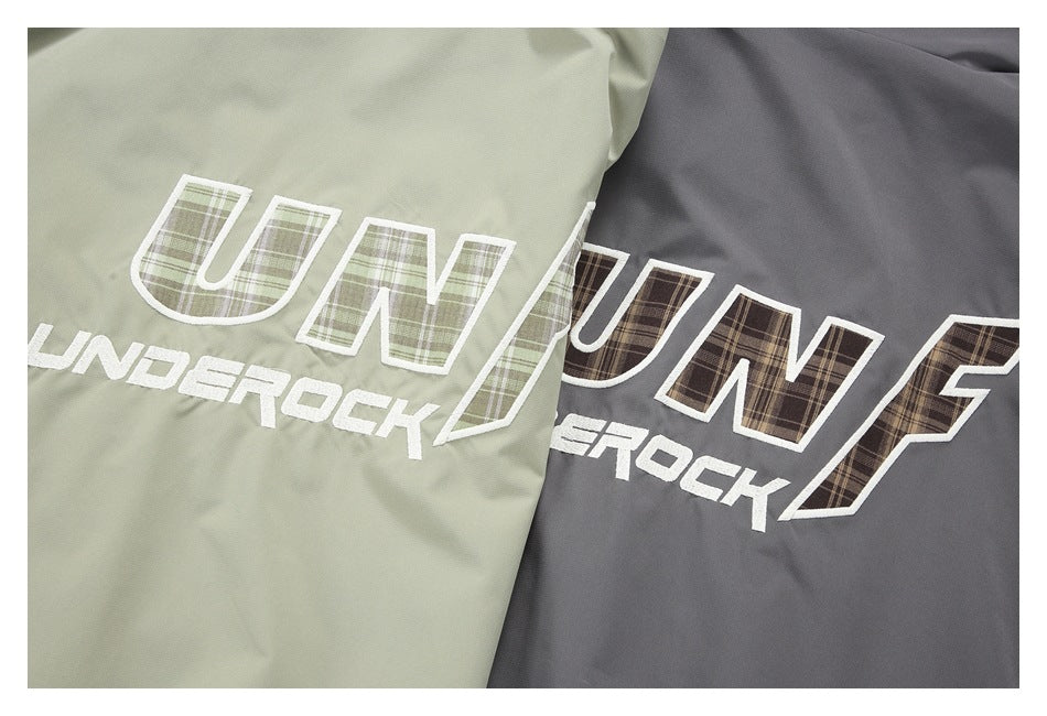Close-up of plaid-filled outlined lettering and white text on pale sage and charcoal garments.