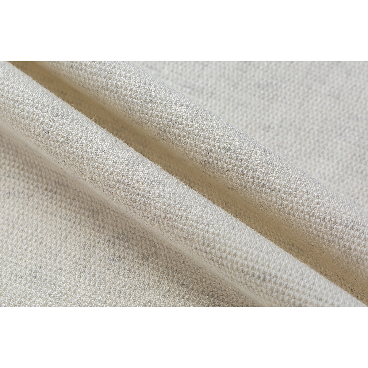 Close-up showing the raised knit texture of off-white shirt fabric folded over itself.