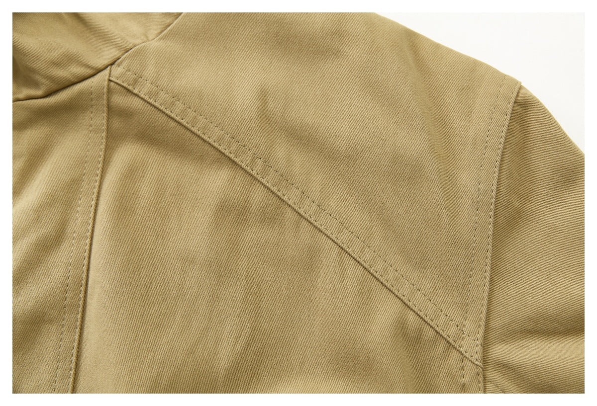 Close-up of tan jacket fabric with a curved shoulder seam and sleeve stitching.