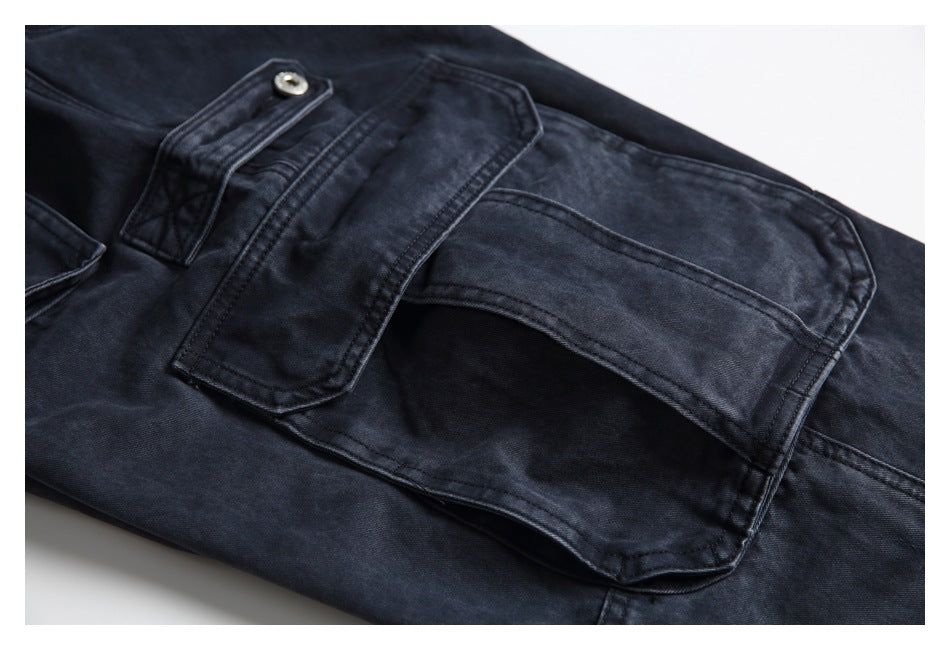 Close-up of a large flap pocket and stitched seams on dark charcoal trousers.