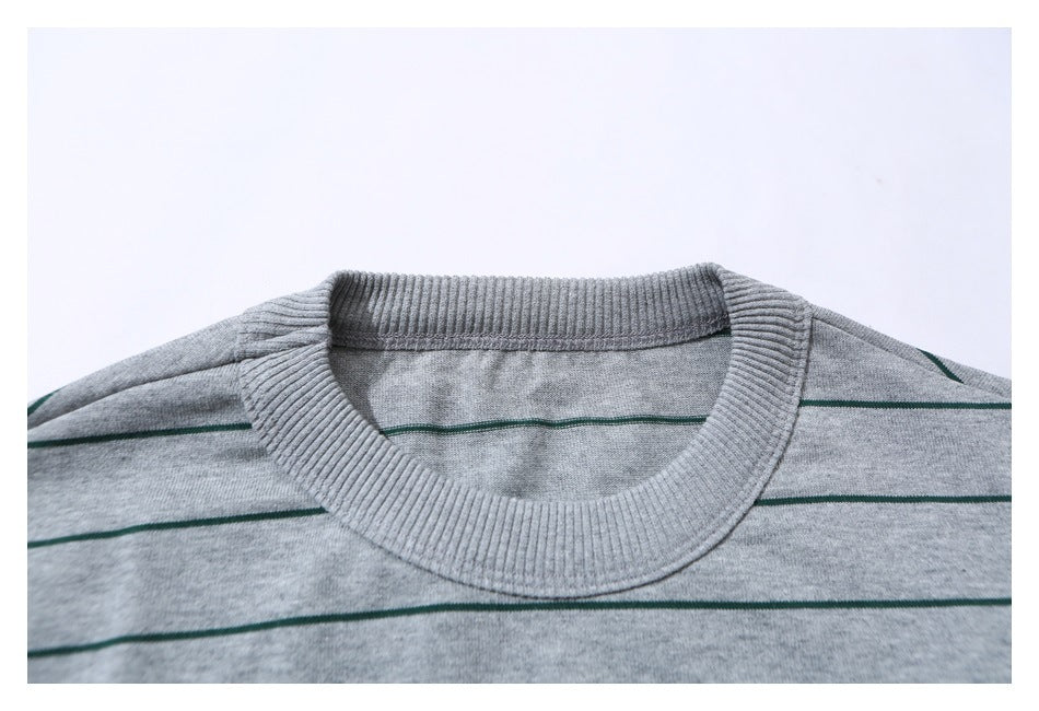 Close-up of a gray T-shirt's ribbed crew neckline and green horizontal stripes.