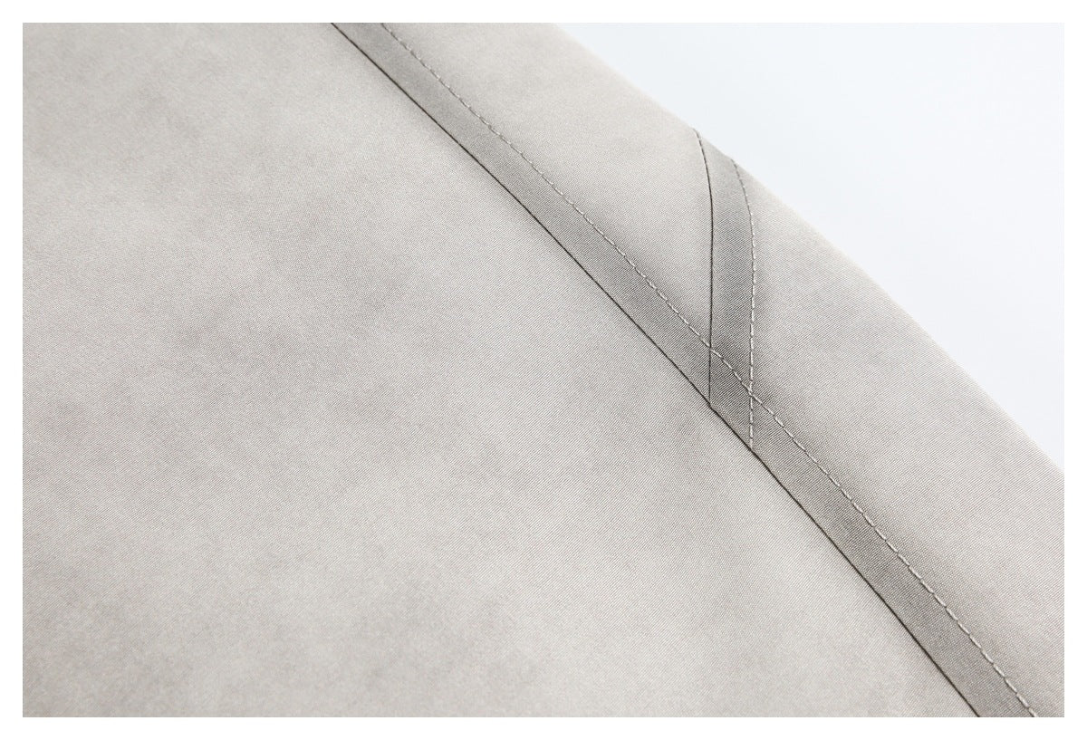 Close-up of light gray jacket fabric and double-stitched seam along a panel.