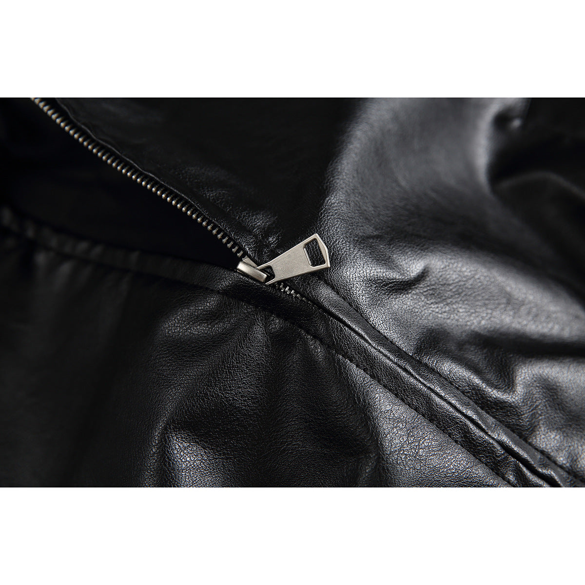 Close-up of the black jacket’s metal zipper pull and textured surface.