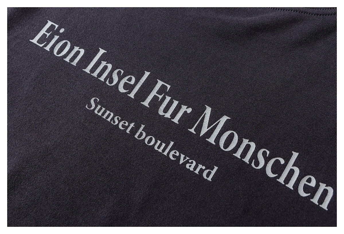 Close-up of white serif lettering reading “Eion Insel Fur Monschen” and “Sunset boulevard” on dark fabric.