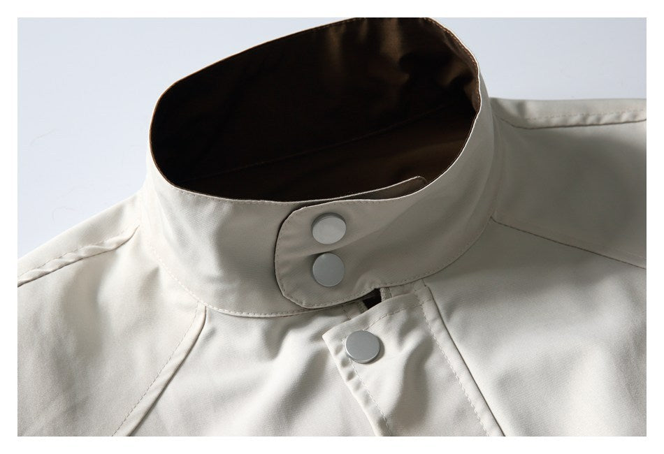Close-up of the ivory jacket's stand collar and snap buttons, with dark brown lining visible inside.